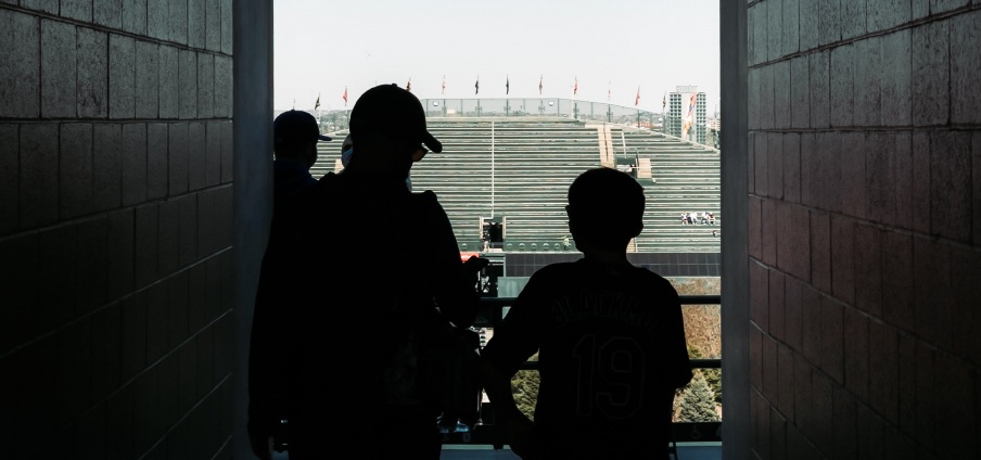 two people in silhouette walking out of tunnel to sports stadium